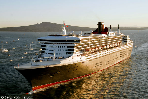 QUEEN MARY 2 (2003/148528grt/IMO 9241061) with the first rays of sun gilding her hull, leaves Rangitoto Ialand astern as she glides into the inner reaches of Aucklands' Waitemata Harbour escorted by hundreds of craft to makie her maiden call at the port during her maiden round the world cruise. 17 February 2007. Photo by SeapixOnline.com/Trevor Coppock